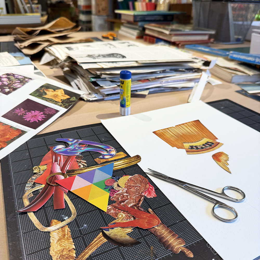 Artistic workspace with cut-out paper designs, scissors, and glue stick on a table.