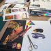 Art supplies including scissors, paper cutouts, and a cutting mat on a table.