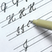 Pen writing on lined paper with a focus on letter formation.