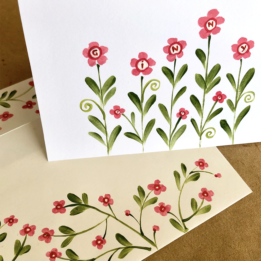 Floral design on a card with pink flowers and green leaves.