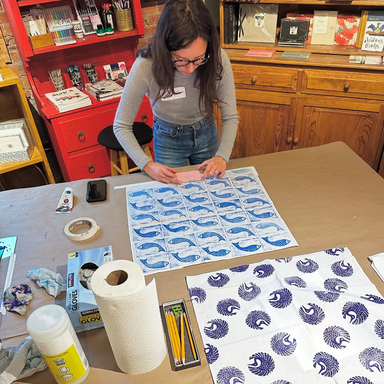 Printing on Fabric class student with stamping in progress- blue stamp fish pattern on fabric