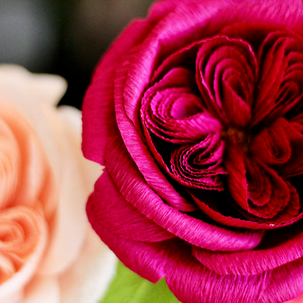Close-up of a pink and peach-colored paper flower against a blurred background