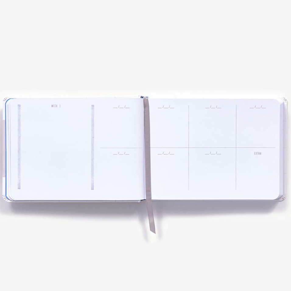 An open white weekly planner style page for swatching daily watercolors  with minimalist gray printed layouts and a thin gray ribbon bookmark, photographed on a clean white background.